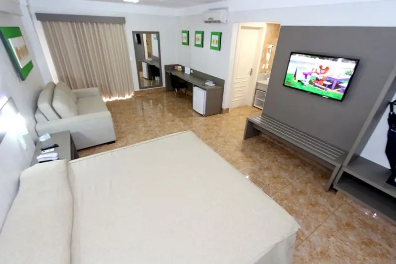 Conforto e elegância em cada detalhe: suíte ampla com cama king-size, sofá, ar-condicionado e decoração moderna no Therma Di Roma, em Caldas Novas.