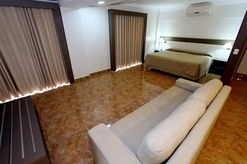 Conforto e elegância em cada detalhe: suíte ampla com cama king-size, sofá, ar-condicionado e decoração moderna no Therma Di Roma, em Caldas Novas.