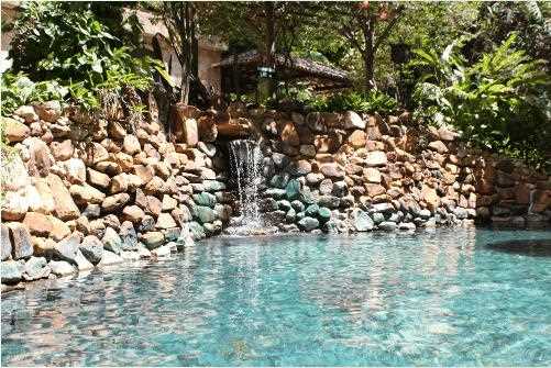 Um convite ao relaxamento: piscina de águas termais com cascata, perfeitamente integrada à natureza exuberante.