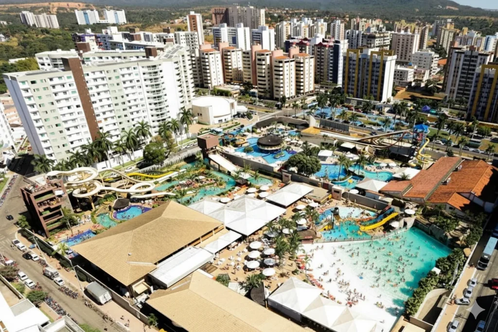 Vista aérea de um grande parque aquático densamente integrado a uma cidade. O parque, cheio de piscinas e toboáguas, está lotado de pessoas e é imediatamente cercado por ruas e altos prédios de apartamentos e hotéis que formam um horizonte urbano denso.