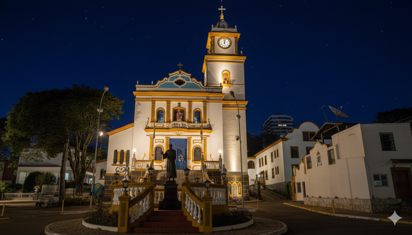 A histórica Igreja Matriz de São Lourenço da Serra, em São Paulo, destaca-se em uma bela noite de céu limpo. A iluminação artificial realça os detalhes de sua arquitetura colonial, desde a torre do relógio até a estátua de seu padroeiro, criando uma atmosfera serena e acolhedora no centro da cidade.