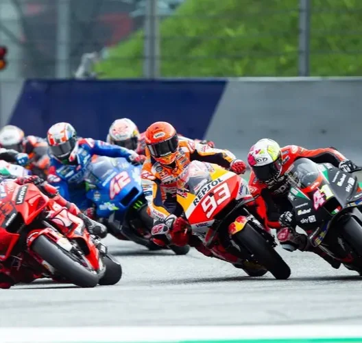 Com certeza! Com base na descrição detalhada e no guia, aqui estão as sugestões de legenda, título e texto alternativo para a imagem, focando no contexto do MotoGP e do Brasil 2026: Sugestões para a Imagem: Título: Aceleração Máxima: O Retorno Estrondoso da MotoGP ao Brasil em 2026 Legenda: "Motores rugindo e disputas milimétricas em uma curva de tirar o fôlego! Esta imagem captura a essência da MotoGP, antecipando a adrenalina que tomará conta do Brasil em 2026. Pilotos no limite, como o icônico #93 da Repsol Honda e a poderosa Ducati em primeiro plano, mergulham em uma batalha intensa, simbolizando o espetáculo inesquecível que aguarda os fãs brasileiros no retorno do Grande Prêmio. Prepare-se para a velocidade, a paixão e a história sendo reescrita!" Texto Alternativo (Alt Text): "Um grupo de motocicletas de MotoGP, incluindo a Repsol Honda #93 e uma Ducati vermelha, em intensa disputa em uma curva para a direita. Os pilotos estão em alta inclinação, com os cotovelos próximos ao asfalto, mostrando a perícia e a velocidade da corrida."
