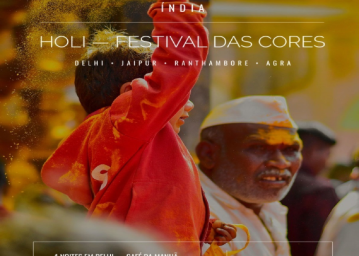Imagem promocional de viagem para a Índia com foco no Festival Holi, mostrando uma criança de moletom vermelho jogando pó colorido para o alto. Ao fundo, um homem sorri com o rosto marcado por pigmentos amarelos. O texto na imagem detalha o roteiro passando por Delhi, Jaipur, Ranthambore e Agra, com o valor de USD 5.718 e início da viagem em 18 de março de 2027.