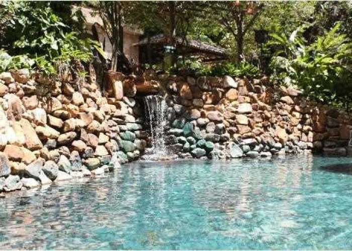 Um convite ao relaxamento: piscina de águas termais com cascata, perfeitamente integrada à natureza exuberante.